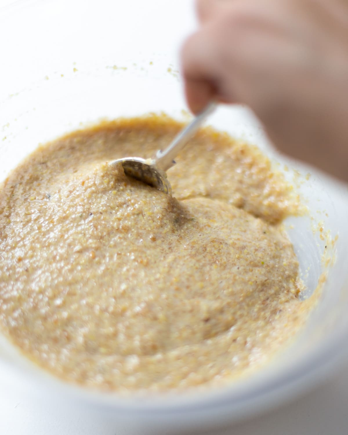 A bowl of finished flaxseed pudding being stirred with a metal spoon.