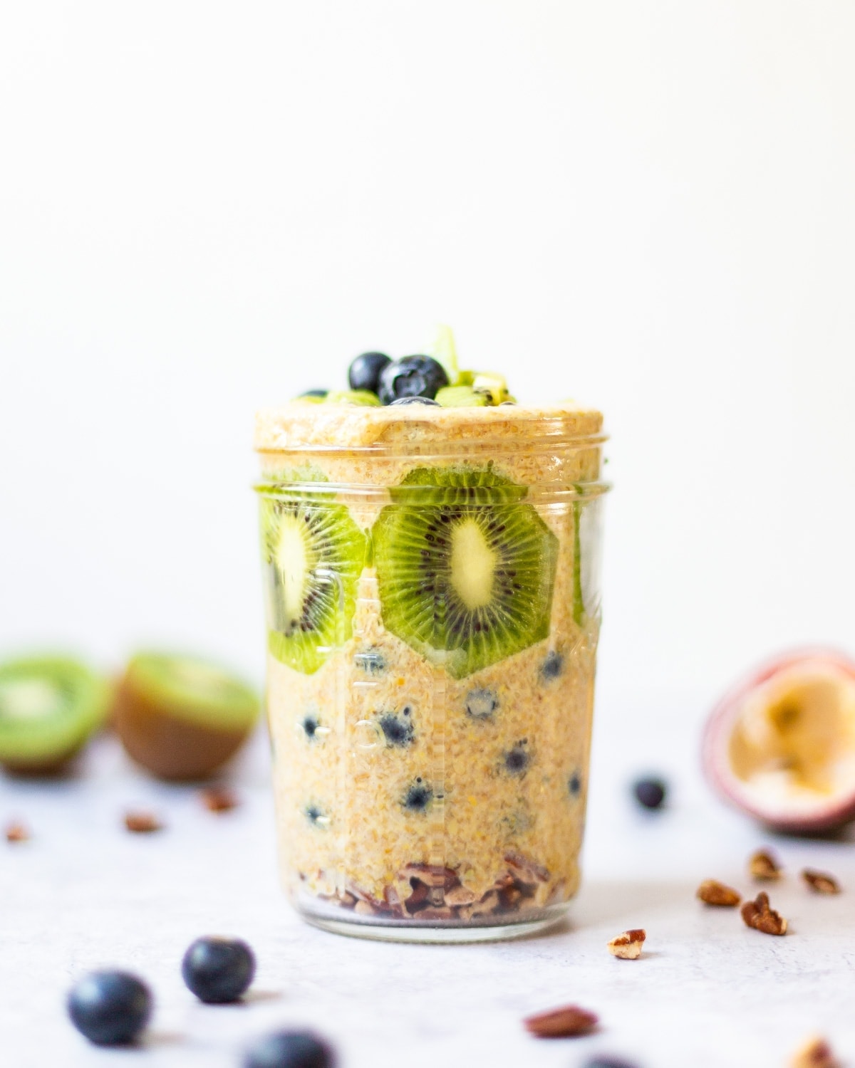 A side on view of a mason jar filled with flaxseed pudding, fresh fruit and nuts.