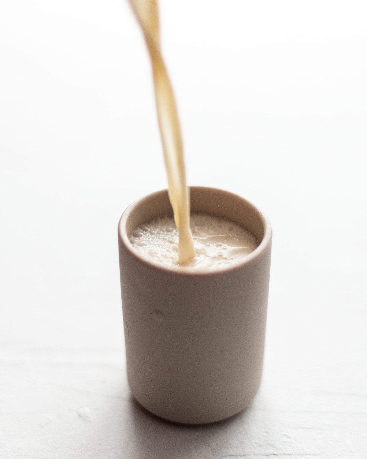 Cashew milk being poured into a childs cup.