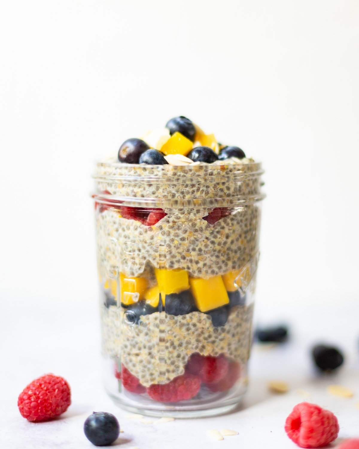 Chia and flaxseed pudding in a jar layered with raspberries, blueberries and diced mango.