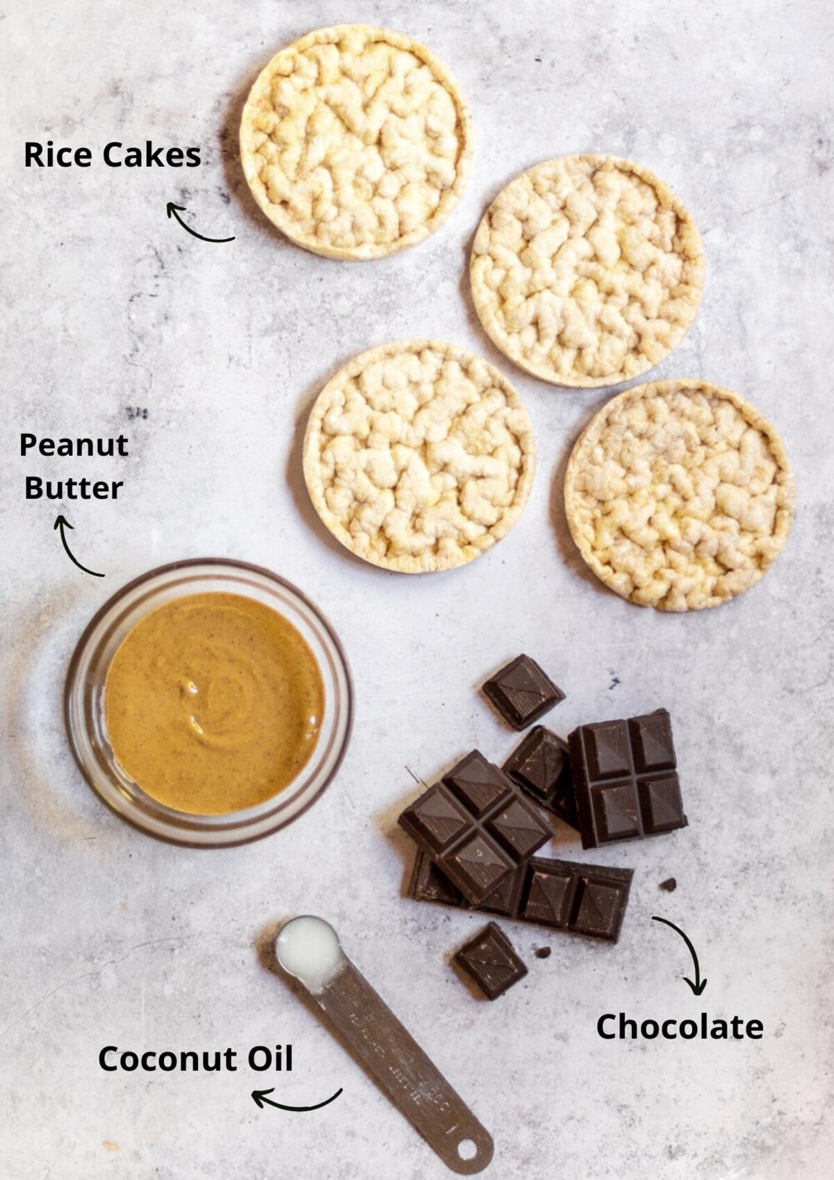 The rice cakes, peanut butter, chocolate and coconut oil laid out on a light background and labelled.