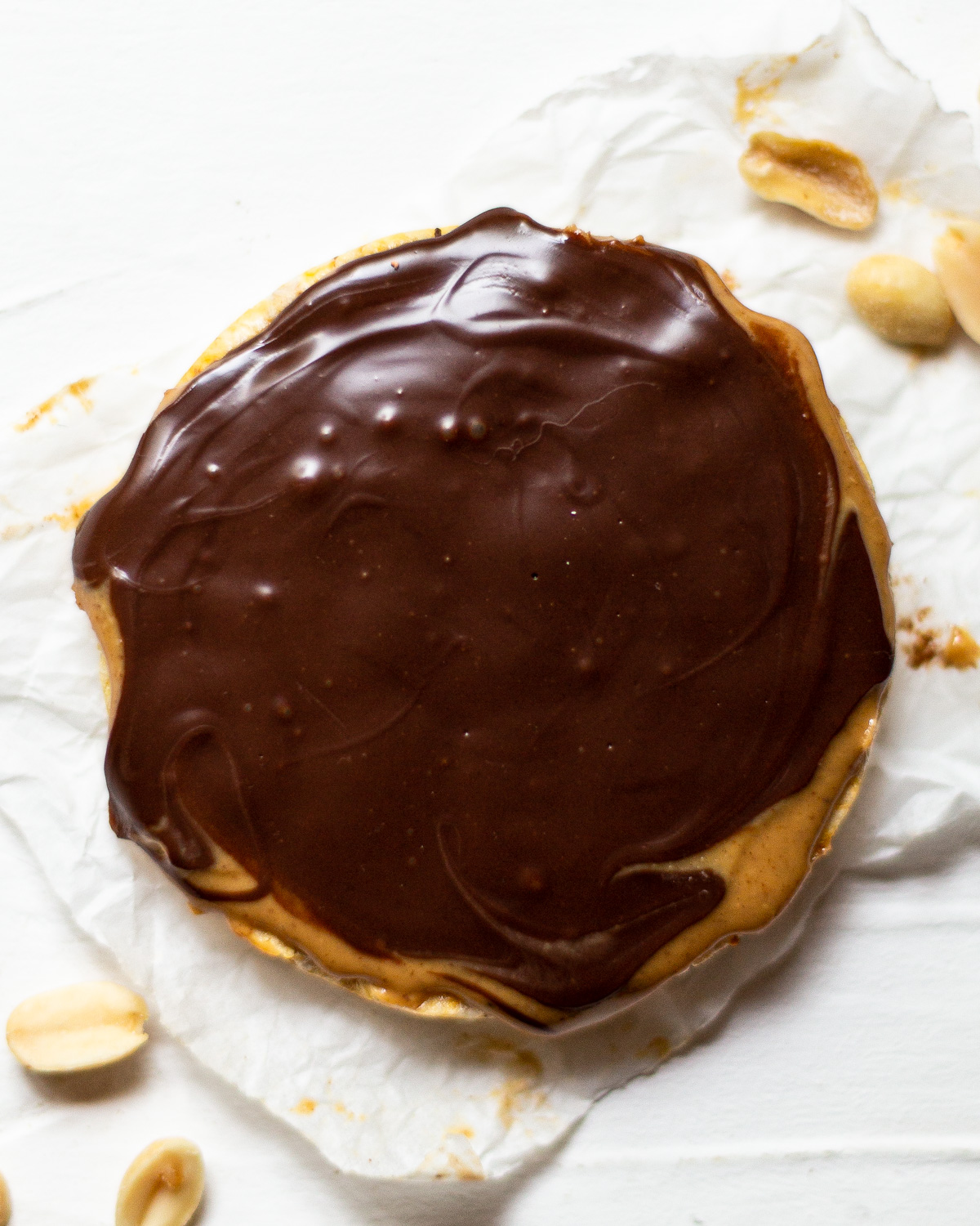 A rice cake, topped with creamy peanut butter and melted chocolate.