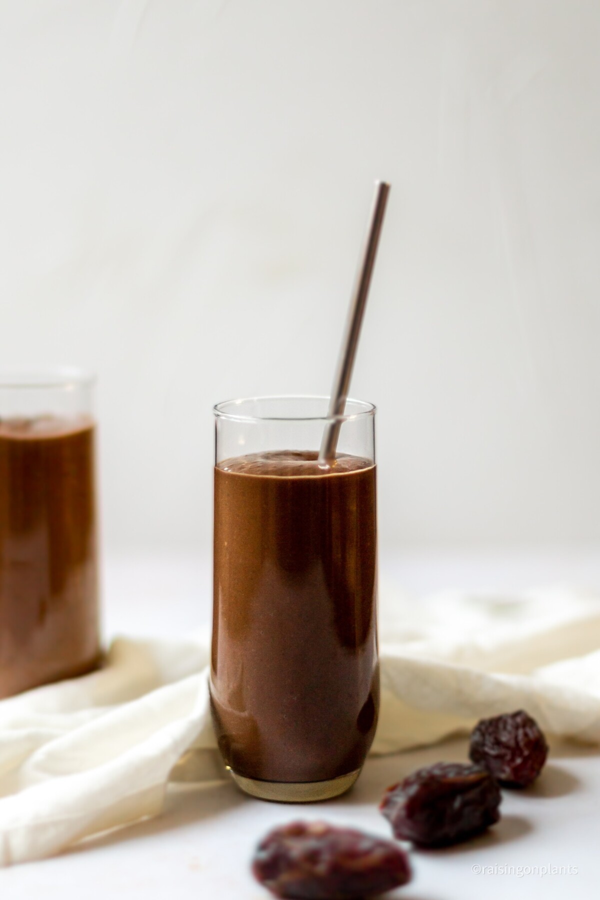 A glass of black bean smoothie with a straw.