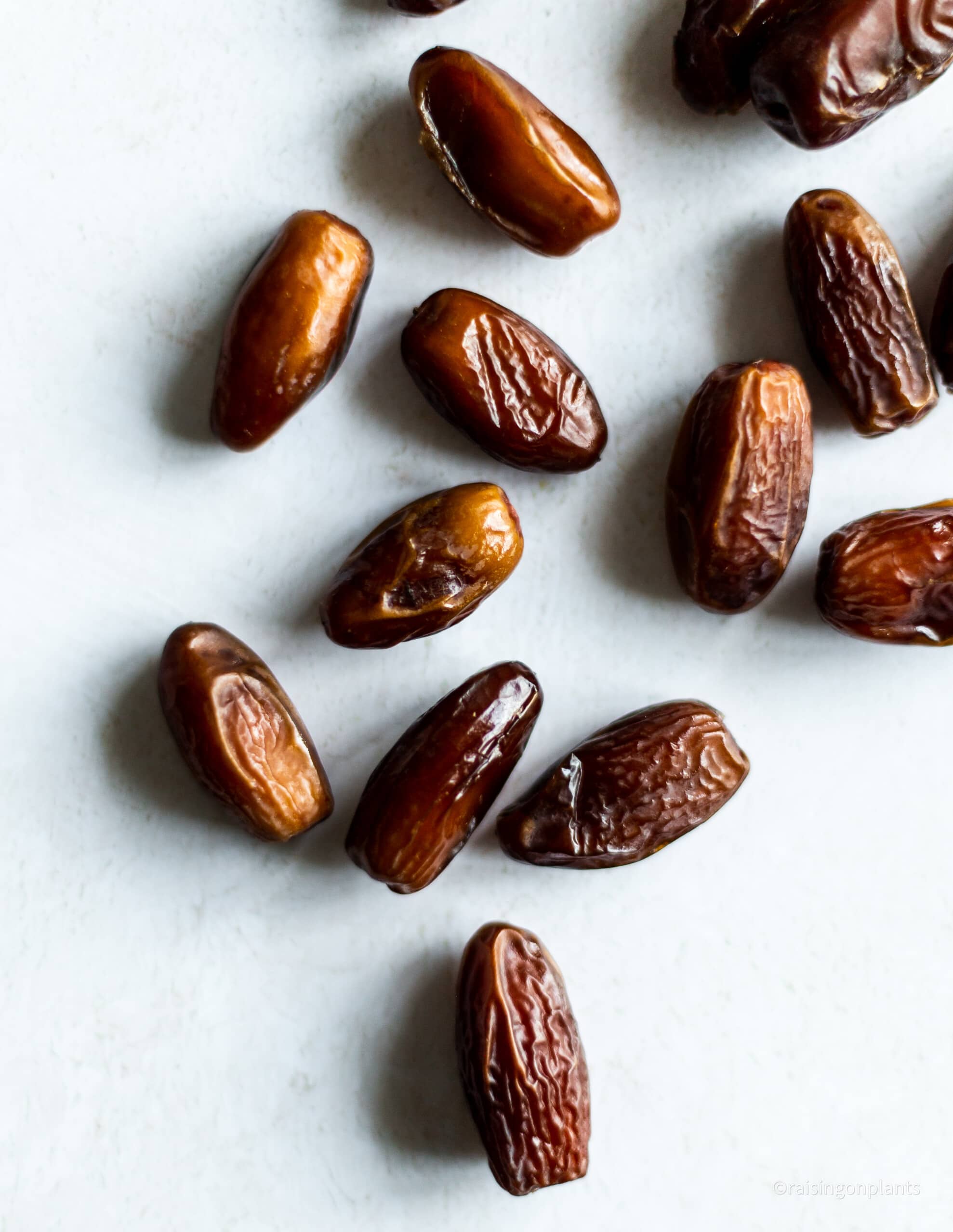 Scattered deglet noor dates on a white background.