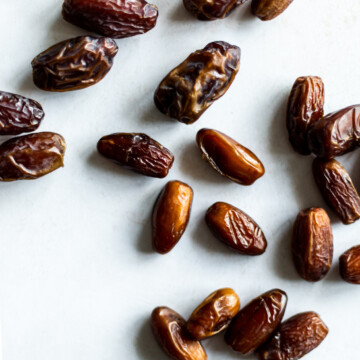 Medjool and deglet noor dates scattered over a white background.