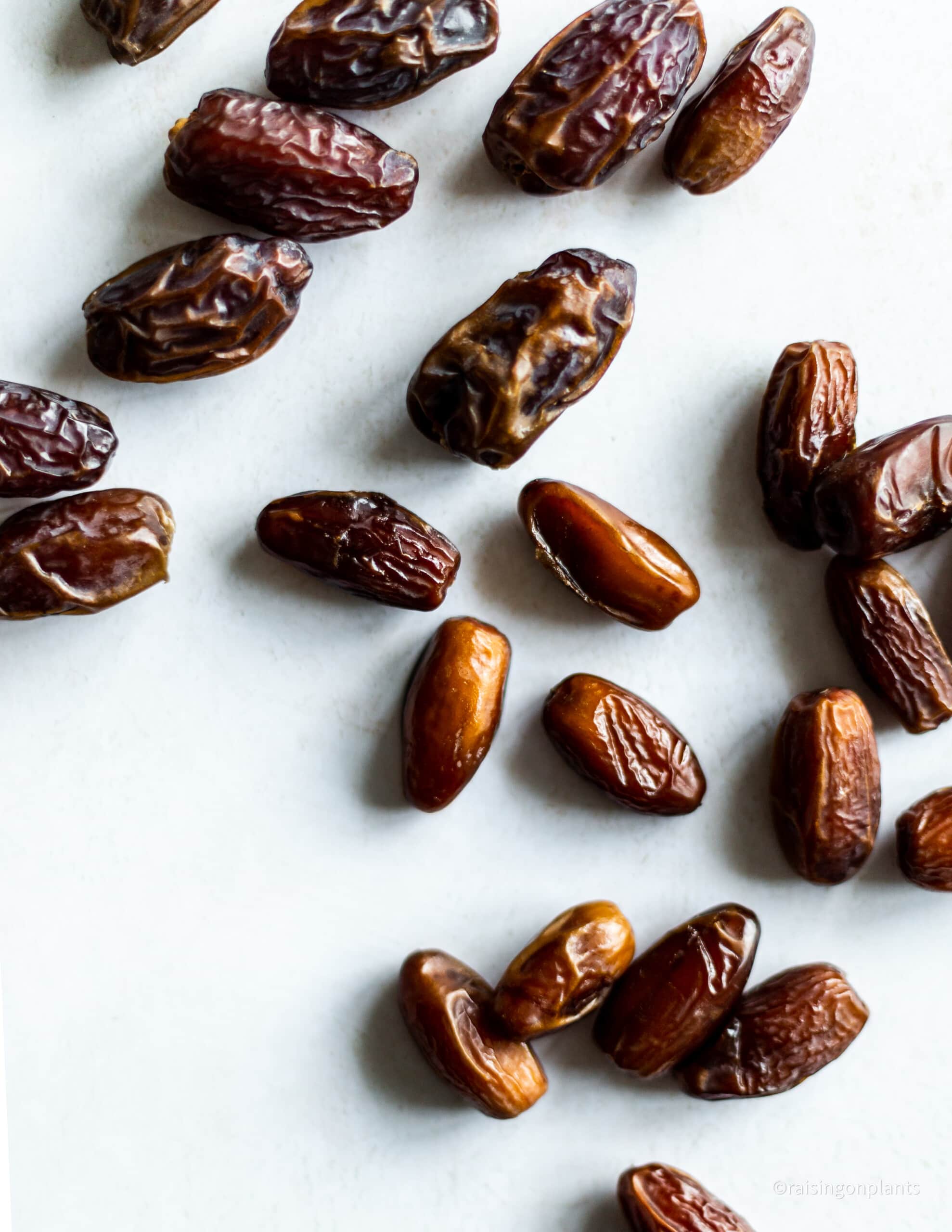 Medjool and deglet noor dates scattered over a white background.