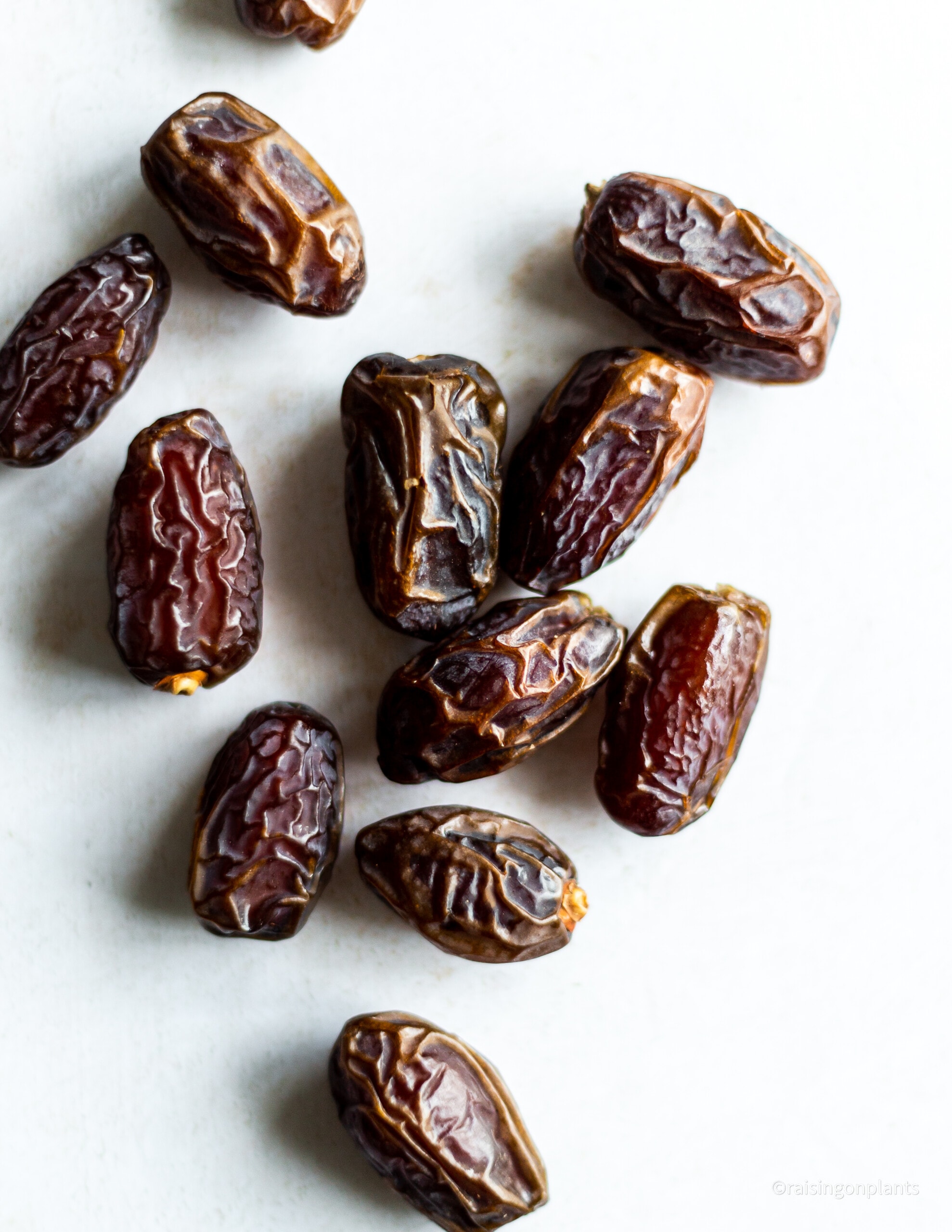 Whole medjool dates scattered on a white background.